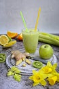 Closeup green smoothie, celery, lemons and kiwi, ginger root and daffodils on a gray marble background. v Royalty Free Stock Photo