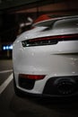 Closeup of a grey Porsche car rear with the spoiler at a parking spot.