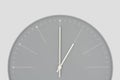 Closeup of a grey wall clock isolated on light grey background. One o`clock. Time. Minimal styled