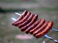Closeup grilled sausages browning on grill outdoors. Royalty Free Stock Photo