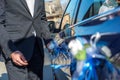 Closeup groom decorates wedding car with artificial flowers. Wedding preparation