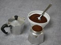 Closeup of ground coffee in the bottom valve of a moka pot on a gray surface