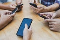 Closeup of a group of people holding their smartphones with black screens around a table