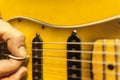 Closeup of guitarist fingers holding plectrum on strings of electric guitar