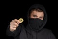 Closeup hacker with blurred face hold bitcoin in hand initiating cyber attack, concept cyber security, on black