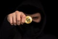 Closeup hacker with blurred face hold bitcoin in hand initiating cyber attack, concept cyber security, on black