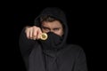 Closeup hacker with blurred face hold bitcoin in hand initiating cyber attack, concept cyber security, on black