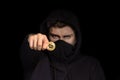 Closeup hacker with blurred face hold bitcoin in hand initiating cyber attack, concept cyber security, on black