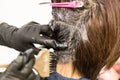 Closeup of hair dresser applying chemical color dye onto hair