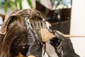 Closeup of hair dresser applying chemical color dye onto hair