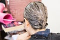 Closeup of hair dresser applying chemical color dye onto hair