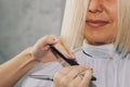 Closeup of a hairdresser cuts wet white hair of a client in a salon. Hairdresser cuts a woman. Side view of a hand cutting hair Royalty Free Stock Photo