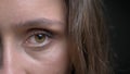 Closeup half-face shoot of young pretty caucasian brunette female face with brown eye looking straight at camera