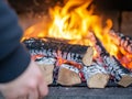 Closeup of a Hand Adding Logs to a Burning Fire Pit Royalty Free Stock Photo