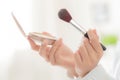 Closeup hand of beauty young asian woman with face looking mirror applying makeup with brush cheek in the bedroom