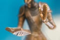 Closeup of the hand of a bronze statue holding an open book and another hand up. Sculpture close up. Small depth of field