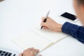 Closeup hand of business man writing on note while using laptop computer on desk at home. Royalty Free Stock Photo