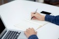 Closeup hand of business man writing on note while using laptop computer on desk at home. Royalty Free Stock Photo