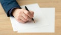 Businessman in the office writes a letter or signs a document on a piece of white paper with a fountain pen with nib. Royalty Free Stock Photo