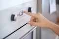 Closeup, hand and button on oven for cooking in kitchen for heating, preparation and appliance. Person, press and switch