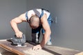 Closeup hand of carpenter, woodworker with professional cutting tool fretsaw or jigsaw, cut wooden tabletop, sawing plank, brown