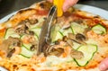 Closeup hand of chef baker cutting pizza at kitchen. Food, italian cuisine and cooking concept. Royalty Free Stock Photo