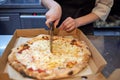 Closeup hand of chef baker in white uniform cutting pizza at kitchen. Royalty Free Stock Photo