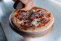 a man cuts a pizza into pieces. Closeup hand of chef baker in white uniform cutting pizza at kitchen Royalty Free Stock Photo