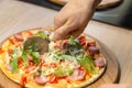 Closeup hand of chef baker in white uniform cutting pizza at kitchen Royalty Free Stock Photo