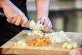 Closeup hand chef cutting up an onion with a knife on board Royalty Free Stock Photo