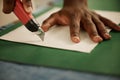 Closeup of hand of designer cutting sample with a knife. Fashion designer cutting paper. African American tailor cutting