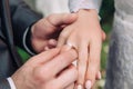 Close-up of the hand of the groom puts a wedding ring on the brides finger, the ceremony on the street, selective focus