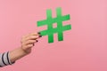 Closeup hand holding big green paper hashtag sign, showing hash symbol as recommendation to follow trends