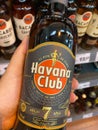 Closeup of hand holding bottle with Havana Club rum in front of shelf in german supermarket