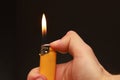 Closeup of a hand holding a burning cigarette lighter on a black blurry background with copyspace Royalty Free Stock Photo