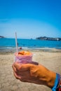 Closeup of hand holding cebiche with beach