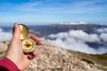 Closeup hand holding compass with mountain and clouds background. Closeup of man tourist hand holding old magnetic Royalty Free Stock Photo