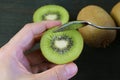 Closeup Hand Holding Cut Kiwifruit Scooping with a Spoon on Black Background Royalty Free Stock Photo