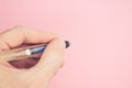 Closeup of a hand holding a fountain pen on pastel pink background with a copy space Royalty Free Stock Photo