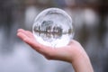 Closeup of hand holding a glass sphere with reflection of trees Royalty Free Stock Photo