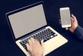 Closeup of hand holding mobile phone with computer laptop background