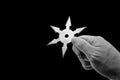 Close up Hand Holding Ninja Star Shuriken Isolated on Black Background with Clipping Path and Copy Space Royalty Free Stock Photo