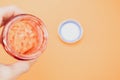 Closeup of a hand holding an open empty strawberry jam jar isolated on light orange background Royalty Free Stock Photo