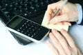 Closeup of a hand holding a pen over blank paper with calculator and laptop Royalty Free Stock Photo