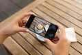 Closeup hand holding phone mobile taking photo coffee on table Royalty Free Stock Photo