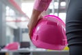 closeup of a hand holding a pink hard hat in an office setting Royalty Free Stock Photo