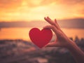 Closeup hand holding red heart during sunset background. Royalty Free Stock Photo