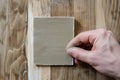 closeup of hand holding sandpaper against wood