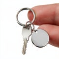 Closeup of Hand Holding Silver Key and Blank Round Keychain with Copy Space on a White Background. Royalty Free Stock Photo