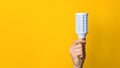 Closeup hand holding white led lighting bulb against a yellow wide background banner with copyspace. concept of idea, energy and Royalty Free Stock Photo